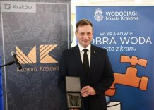 Prezes Wodociągów Miasta Krakowa stoi uśmiechnięty z Medalem.